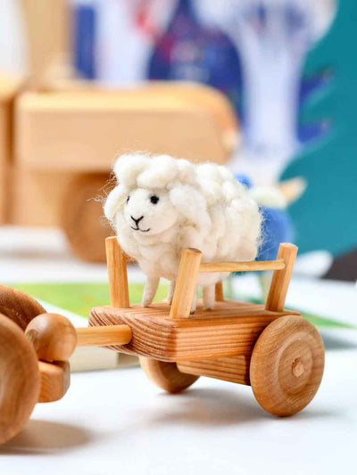 Small white sheep toy on a wooden cart with a blurred background