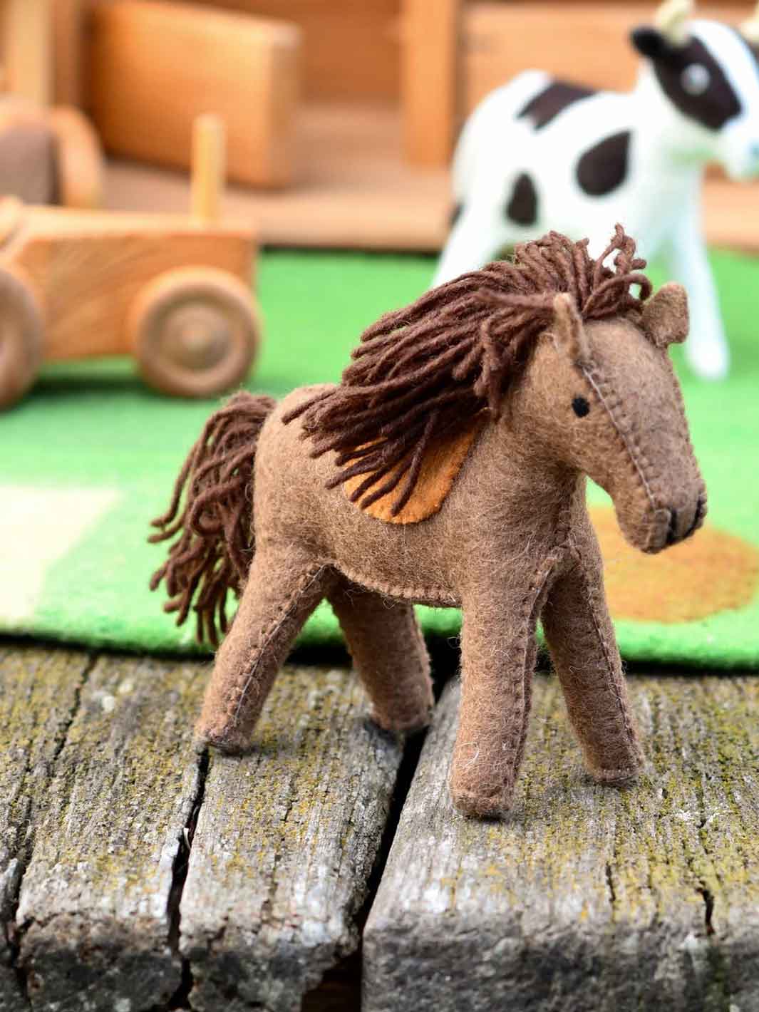 Brown toy horse on a wooden surface with a blurred background of toys