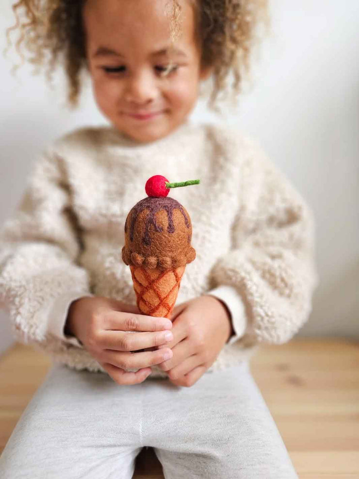 Child holding a felt toy ice cream cone with a cherry on top
