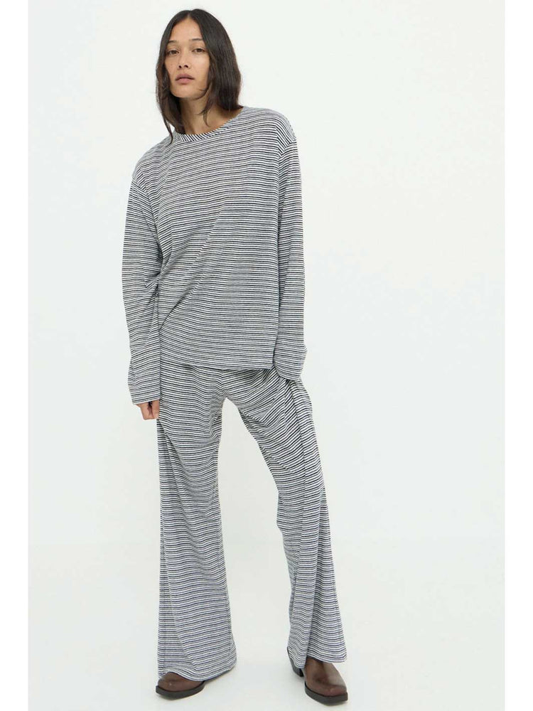 A model wearing a matching two-piece loungewear set consisting of a long-sleeve knit top and wide-leg pants, both in a gray and white horizontal stripe pattern, photographed against a plain white studio background.