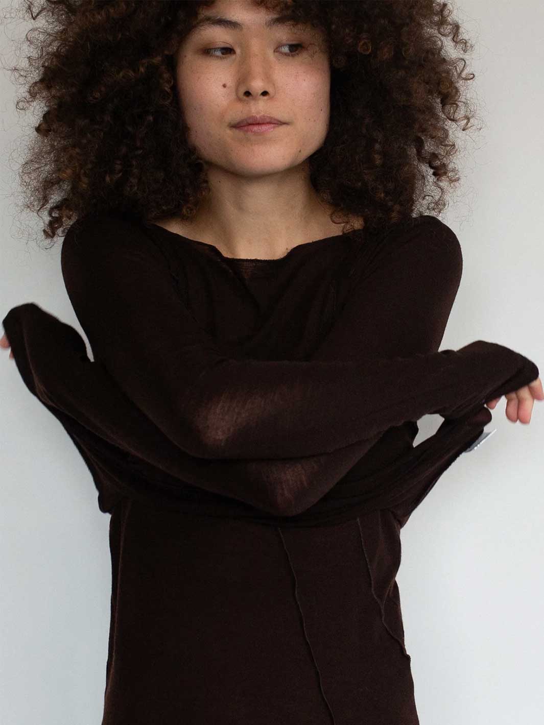 Person wearing a dark brown sweater against a white background