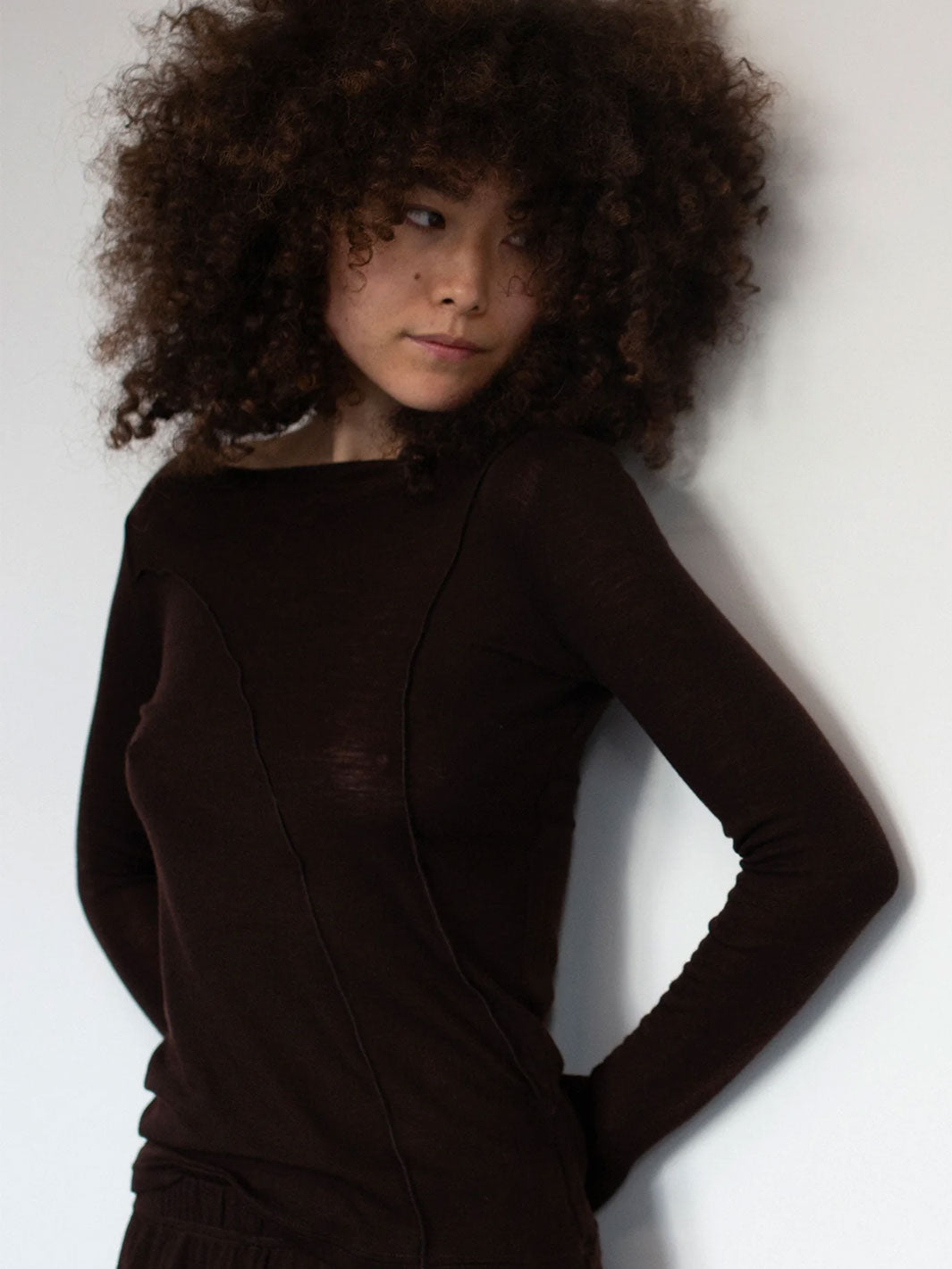 Person wearing a dark brown long-sleeve top against a plain background