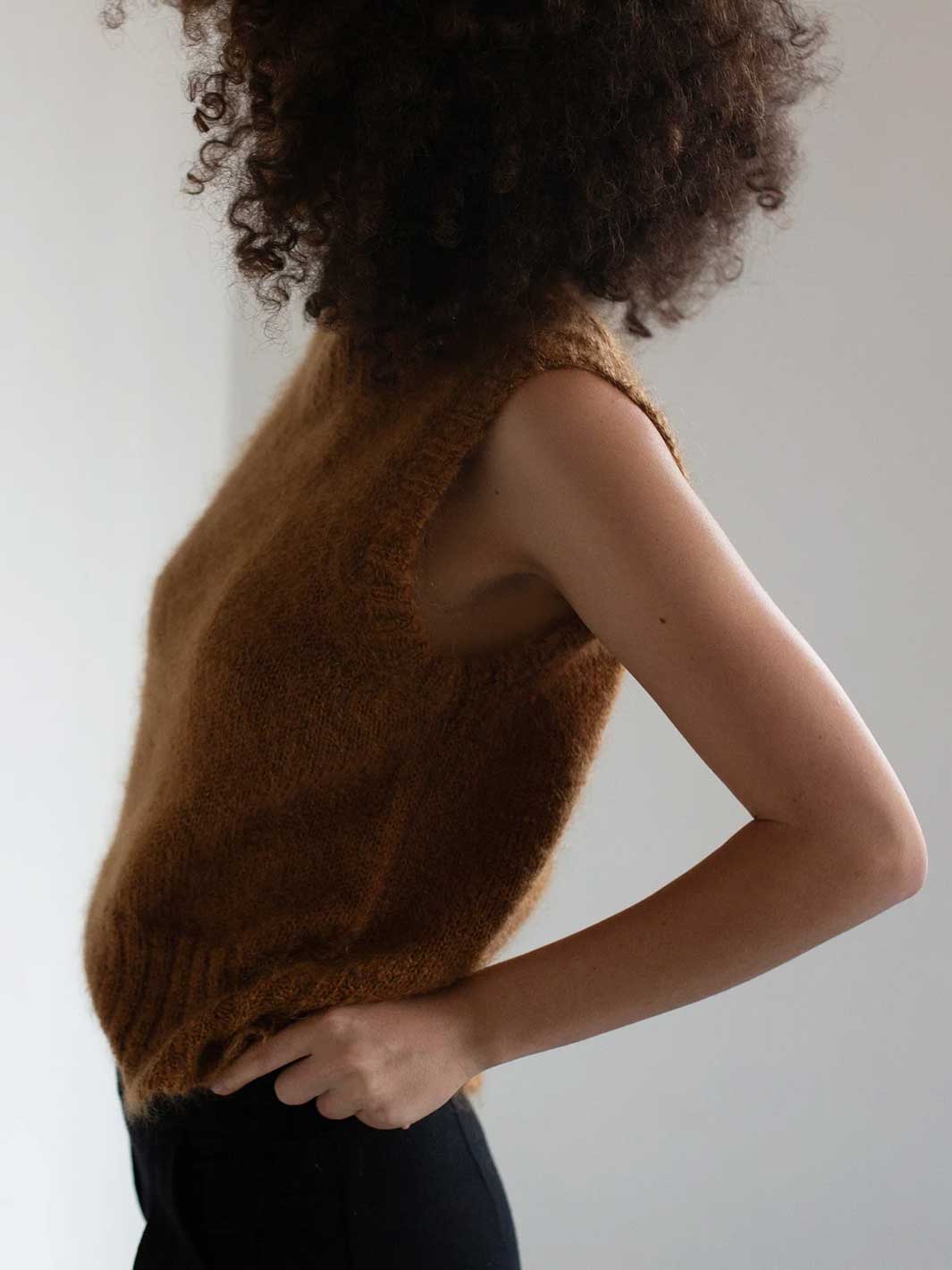 Person wearing a brown mohair wool knit sleeveless vest top against a white background