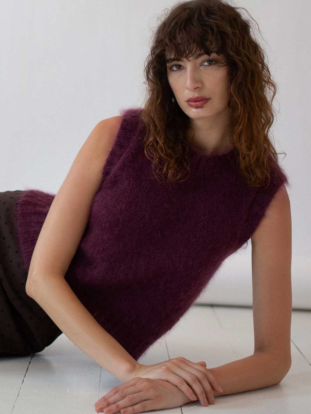 Woman wearing a dark purple sleeveless Mohair Wool knitted vest top on a white background