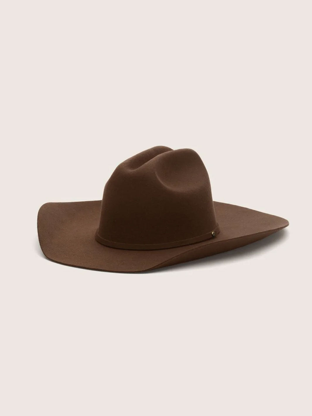 A classic brown felt cowboy hat with a wide brim and a pinched crown, displayed on a solid light beige background.