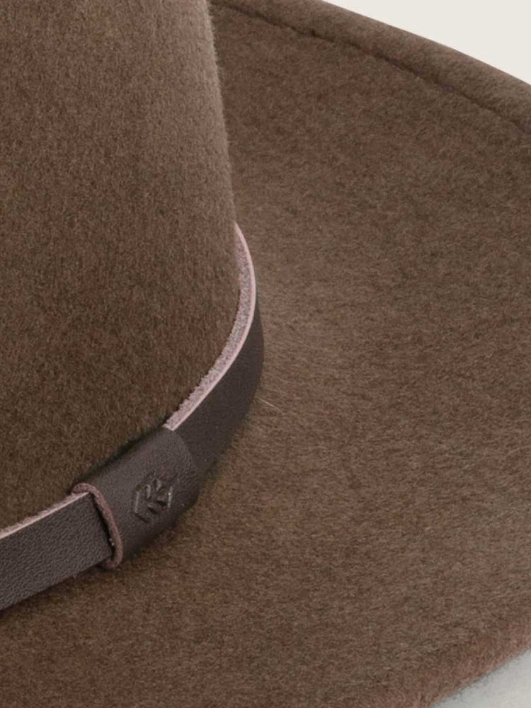 Close-up of a brown kids fedora felt hat with a dark brown leather band featuring an embossed logo.