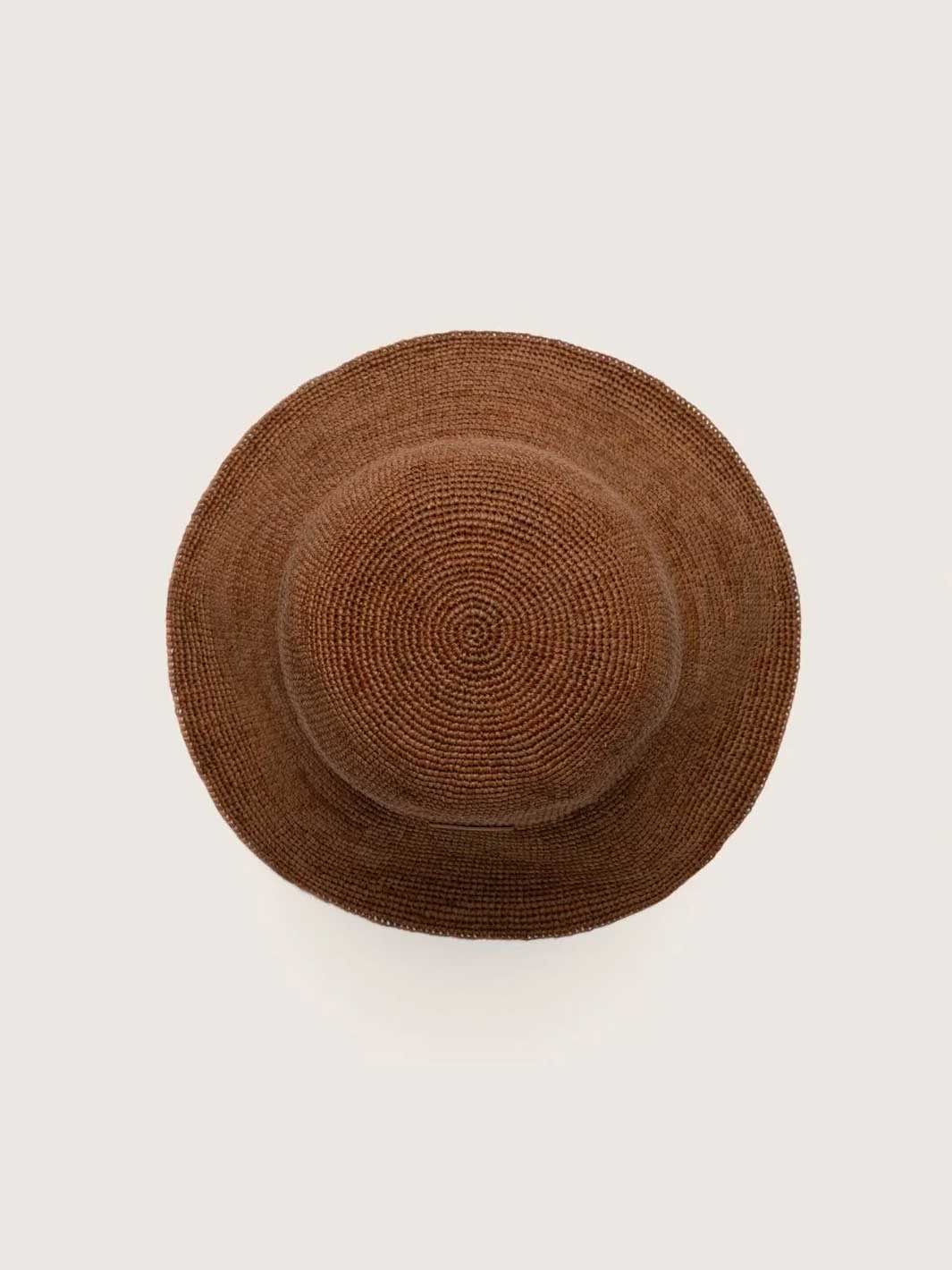 A brown woven straw hat viewed from directly above on a light off-white background.
