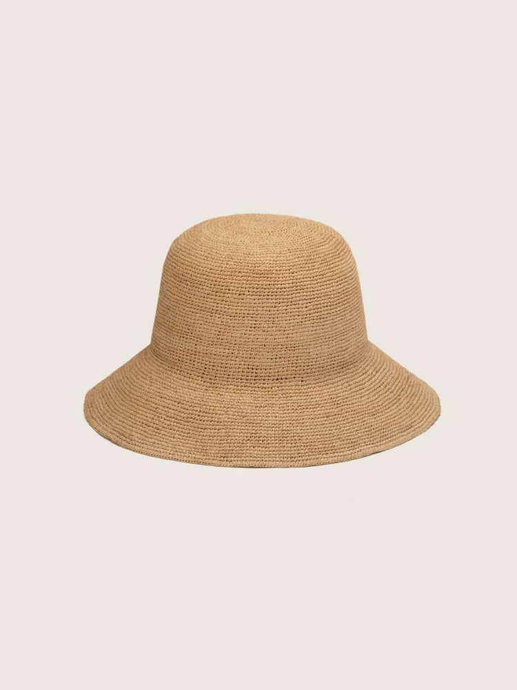 A natural straw bucket hat in a light tan color, shown from a front-facing perspective against a solid, light off-white background.